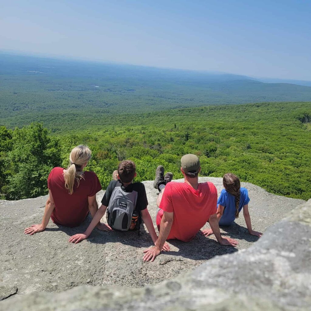 A family of four sits on a rock overlooking at view at Sams Point in New York