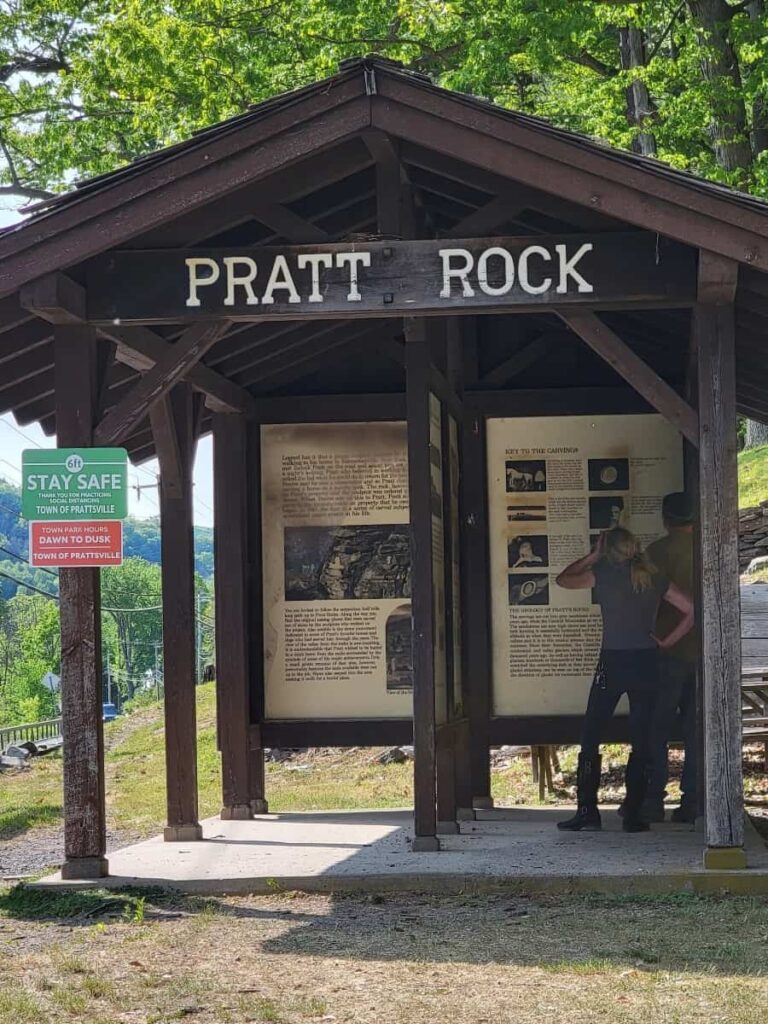 A wooden shelter provides information about the Pratt Rock hike and history of the carvings