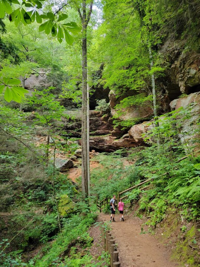 A boy and a girl stand at the bottom of the gorge with rock walls surrounging them