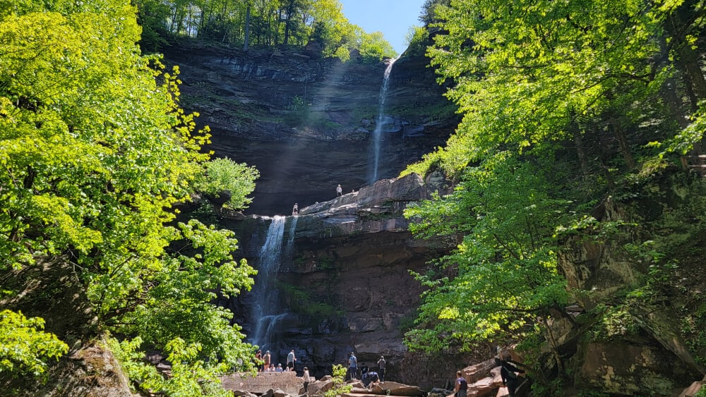 View of two-level waterfall with people in the foreground and trees on the side