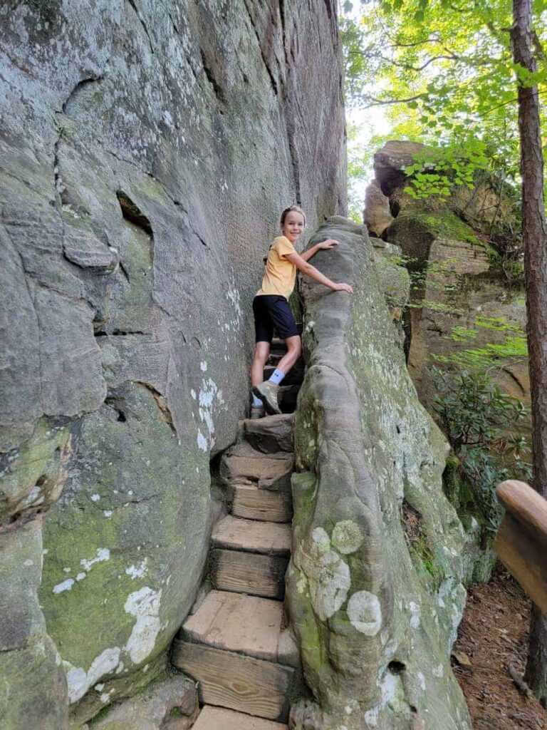 a young girl climbing stone steps up a thin pathway alongside the natural stone arch