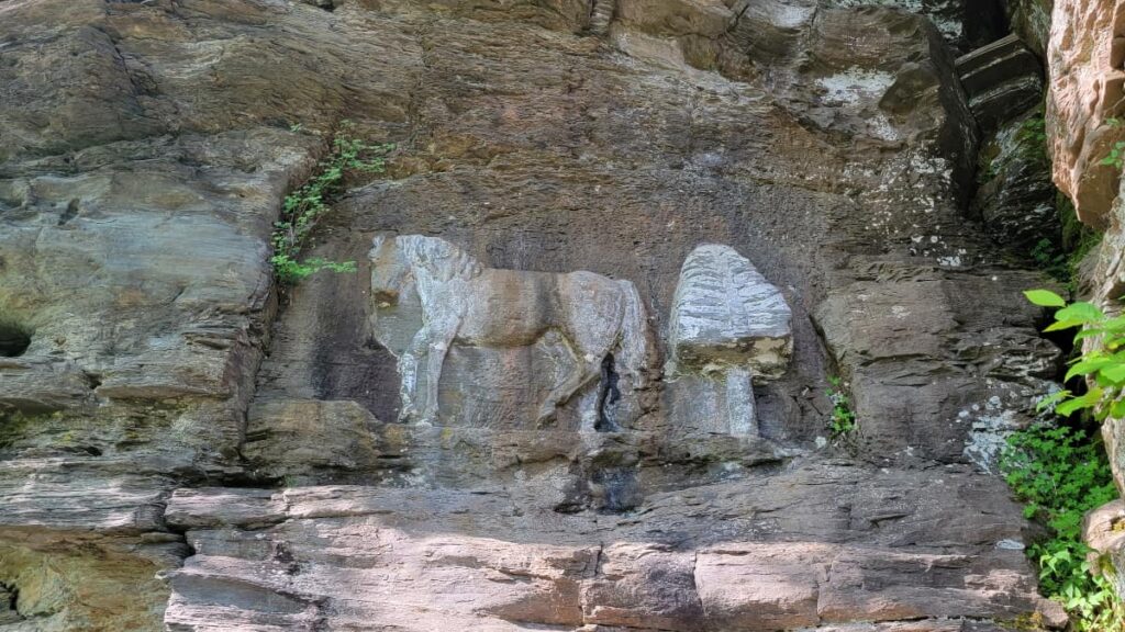 A horse and pine tree are carved out on a rock and painted white to stand out