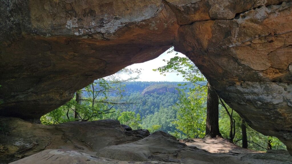 view through a natural stone arch with trees in the distance