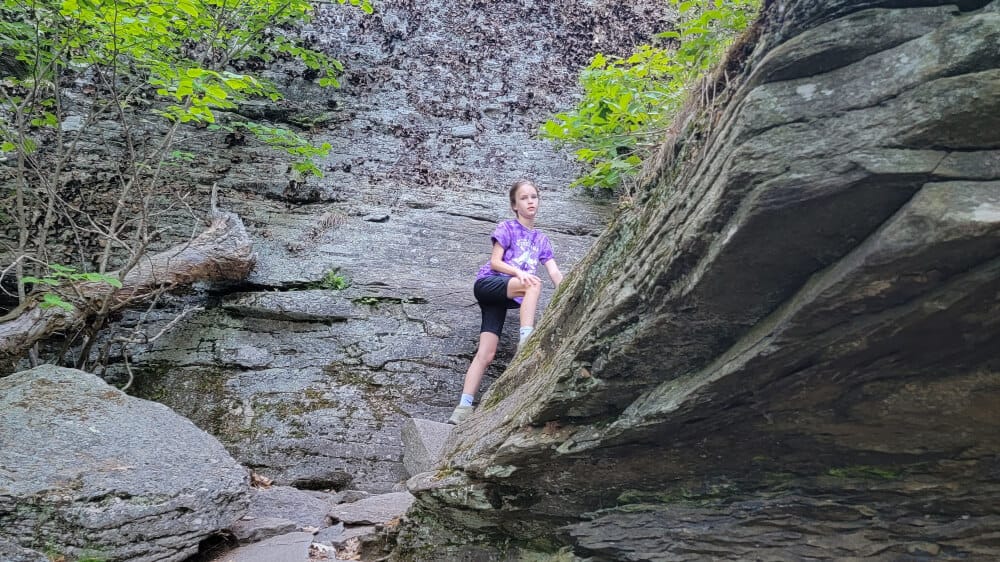 Young girl climbs along big boulders