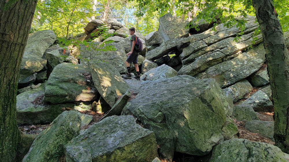 two kids climb over large boulders at Hawk Mountain
