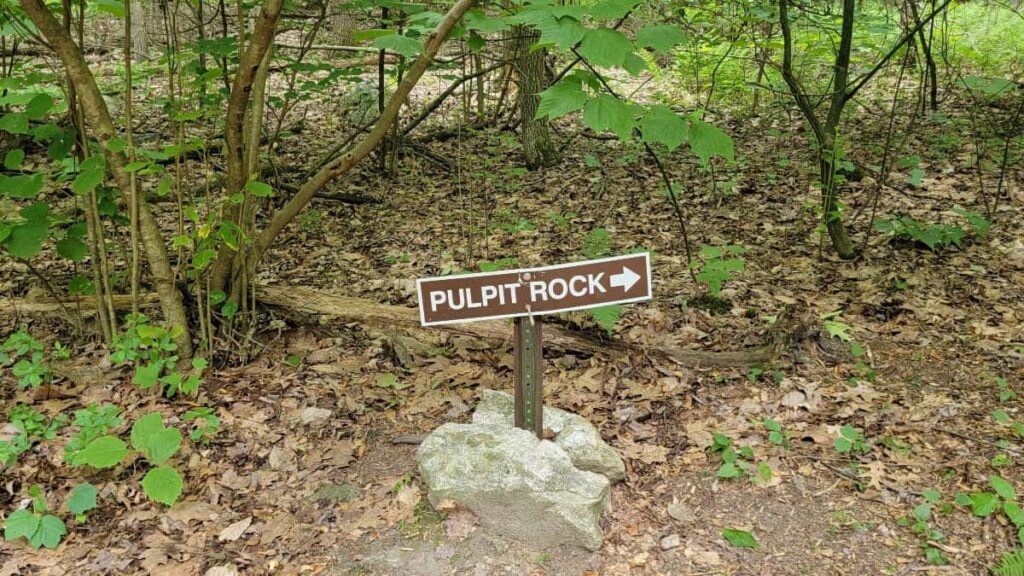 A small sign on a hiking trail reads "Pulpit Rock" with an arrow pointing right