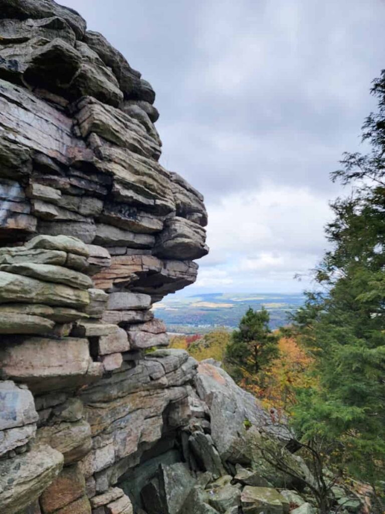 A large rock formation sits on the left while looking down at a valley in the distance