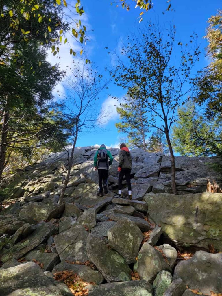 Two kids scramble up angled rocks at Knifes Edge in Pennsylvania