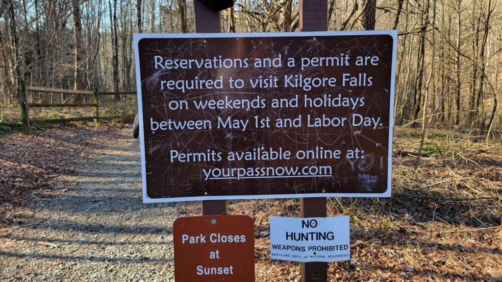 a brown sign with white writing states "reservations and a permit are required to visit Kilgore Falls on weekends and holidays between May 1st and Labor Day"