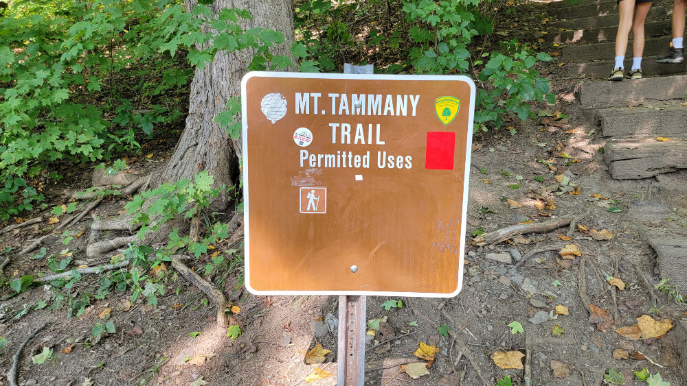 A brown square sign reads "mt. tammany trail: permitted uses" with a hiking icon below