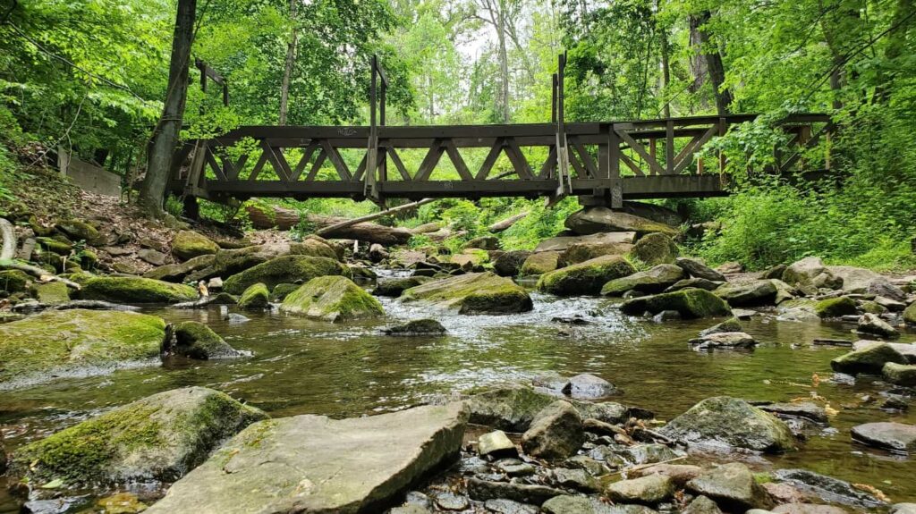 A wooden foot bridge crosses over a small stream with rocks at Tyler State Park