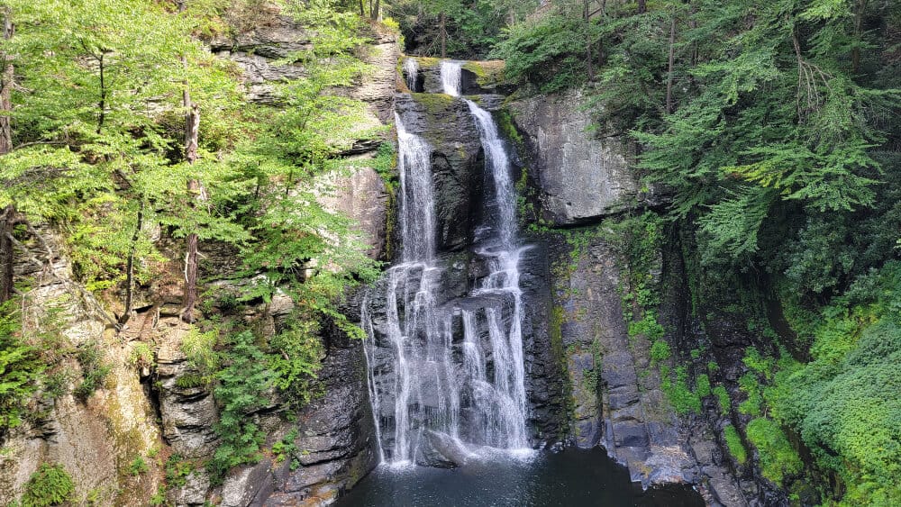 A tall waterfall empties into a large pool at Bushkill Falls 