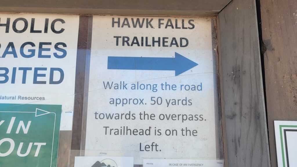 sign at the Hawk Falls parking lot indicating where to find the trailhead