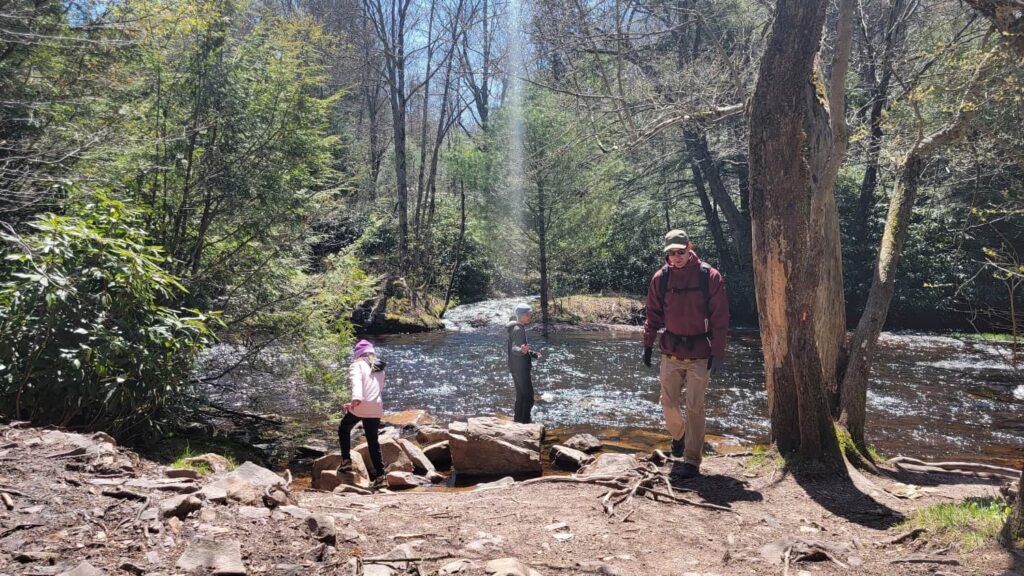 A dad and his two children stand at the bank of a Mud Run Creek along Hawk Falls Trail