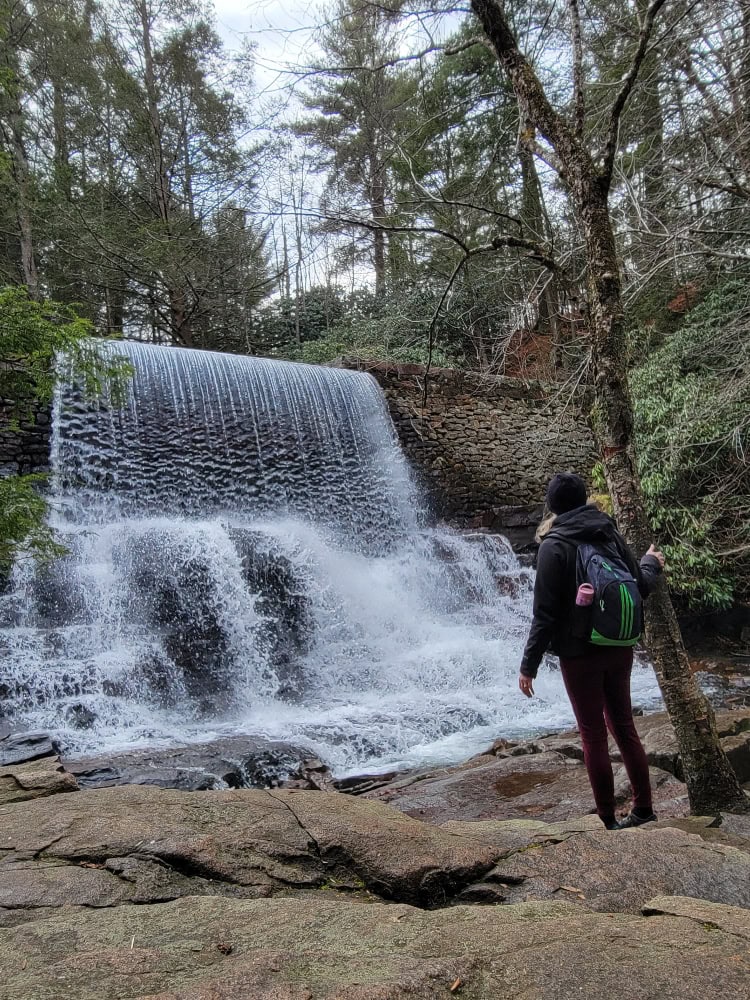 A woman stands in front a man-made waterfall 