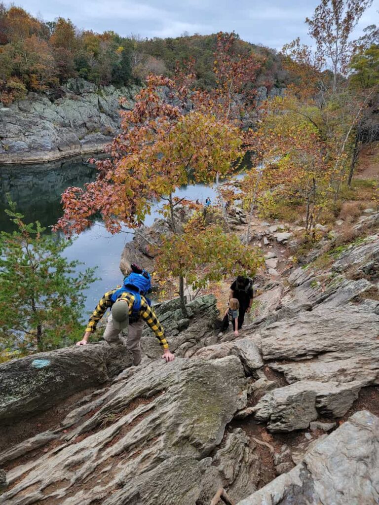 A man climbs up a rock face along the Billy Goat Trail with the Potomac River below