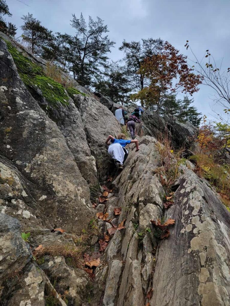 Two kids climb a 50-foot vertical ascent along a rock face at the Billy Goat Trail