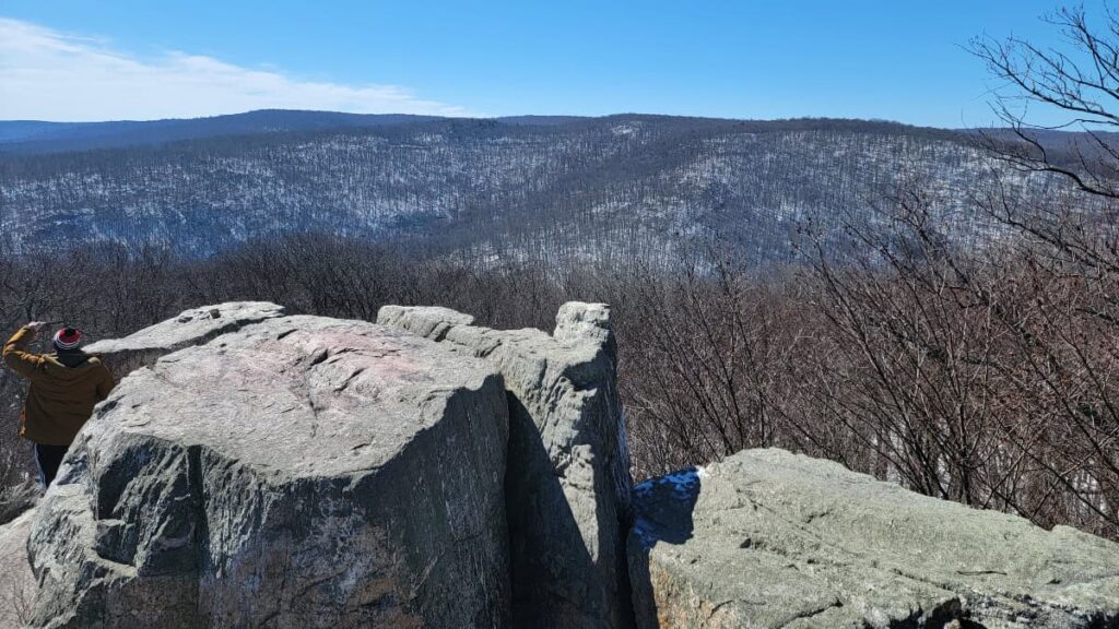Rocks sit in the foreground with a view of snowy mountains in the back at Chimney Rock at Catoctin Mountain Park in Maryland