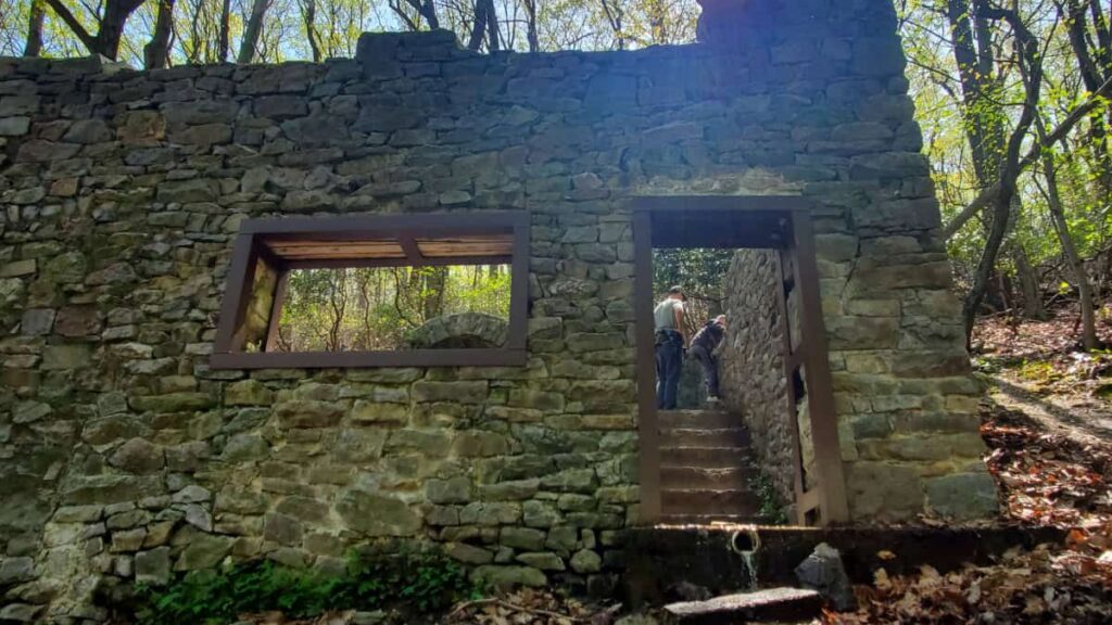 view of the entrance of an old stone building that is now considered ruins, with no roof or door