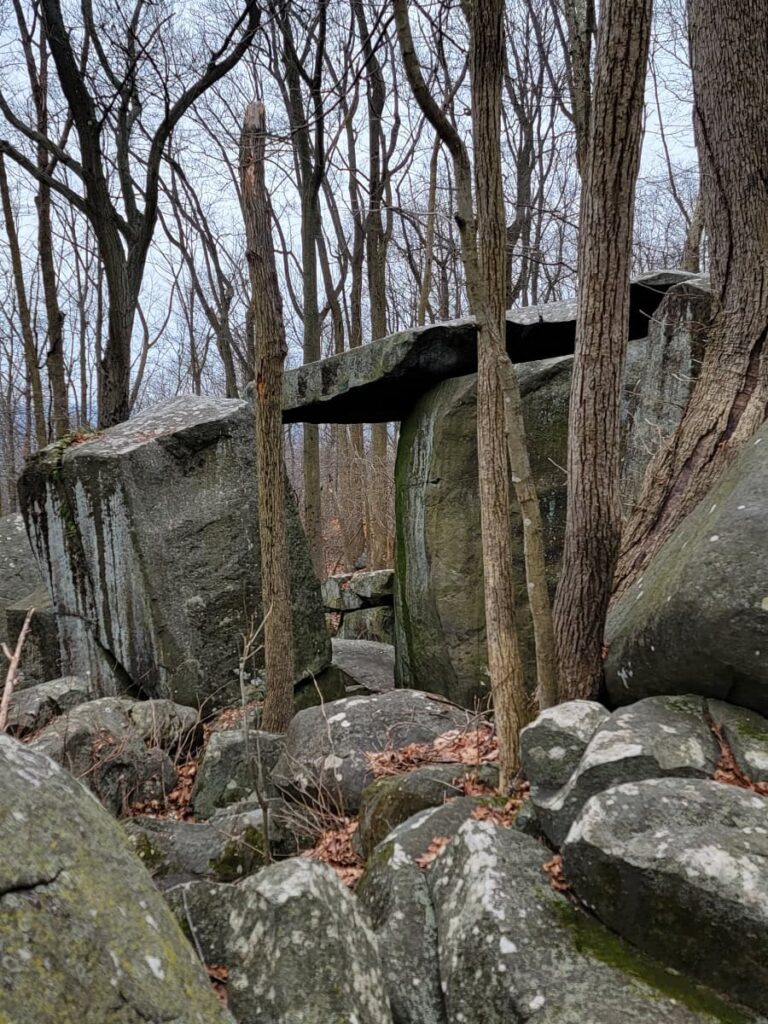 a large flat rock in stacked on two boulders