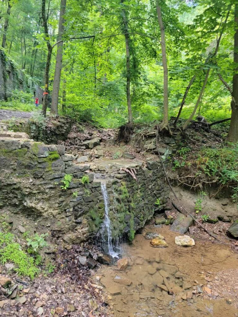 a short waterfall flows with limited water in the summer