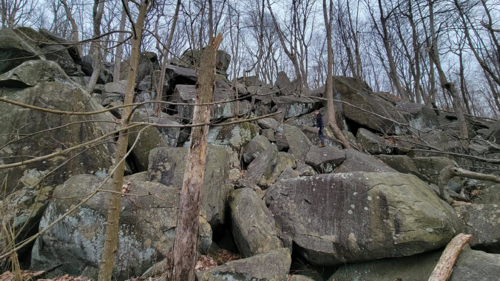 a boy scrambles up a large pile of boulders