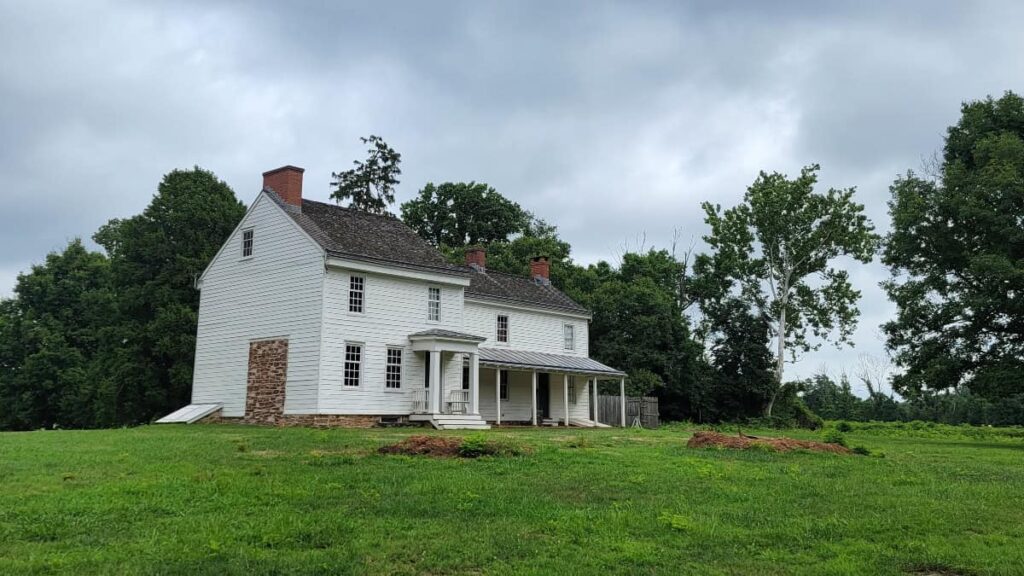 a white farm house sits on a open field