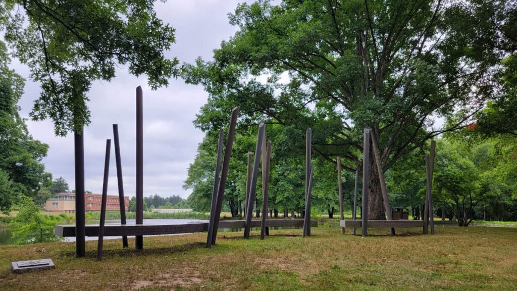 A metal sculpture sits alongside a pond