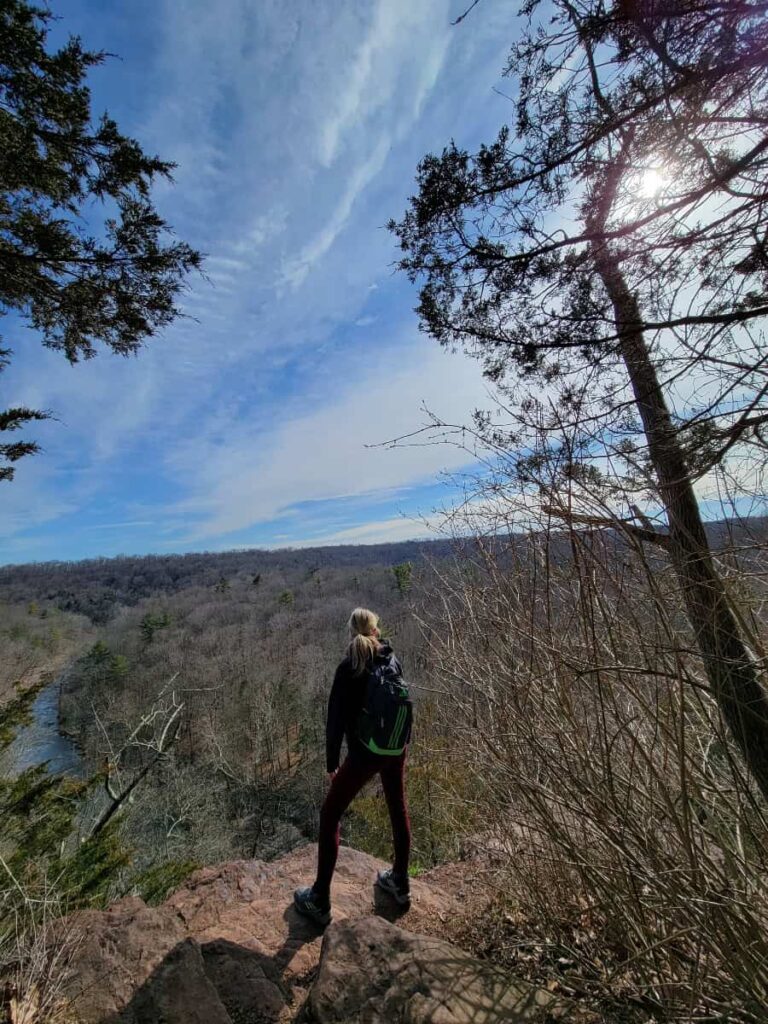 a woman stands at the edge of a cliff overlooking Tohickon Creek at High Rocks