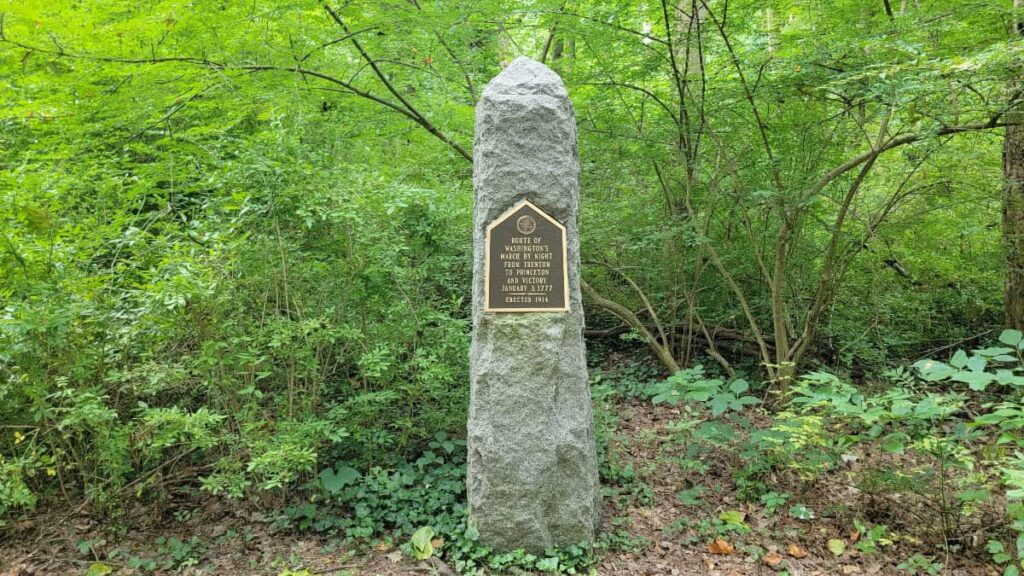 A stone obelisk stands about 5 feet tall with a sign commemorating Washington's march from Trenton to Princeton