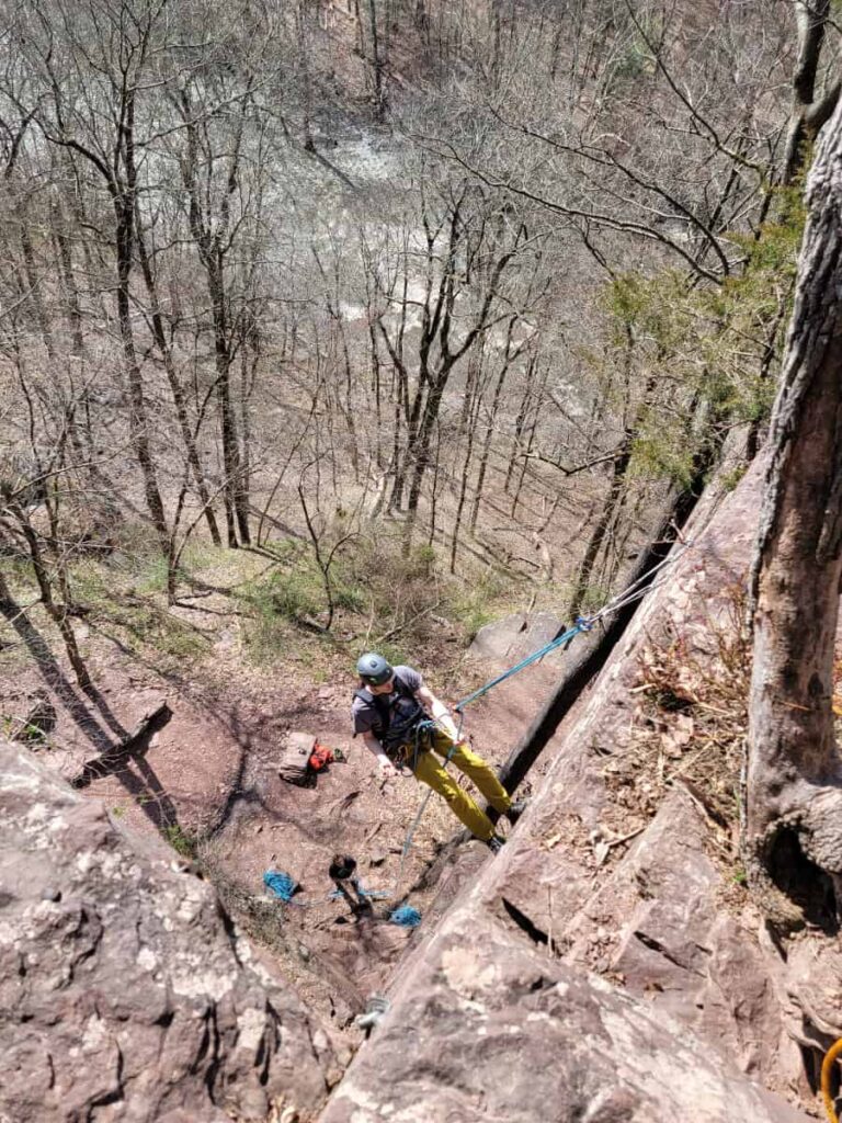 A rock climber rapels down the face of a cliff at High Rocks