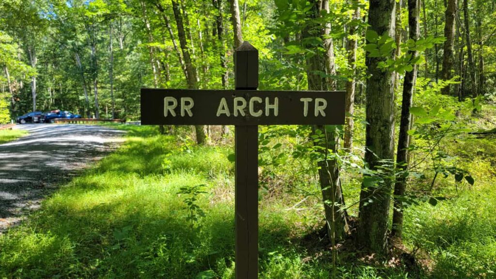 A wooden trail signs reads "RR Arch Tr"