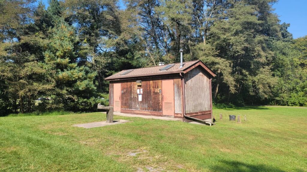 A small building houses two restrooms with vault toilets in Worthington State Forest