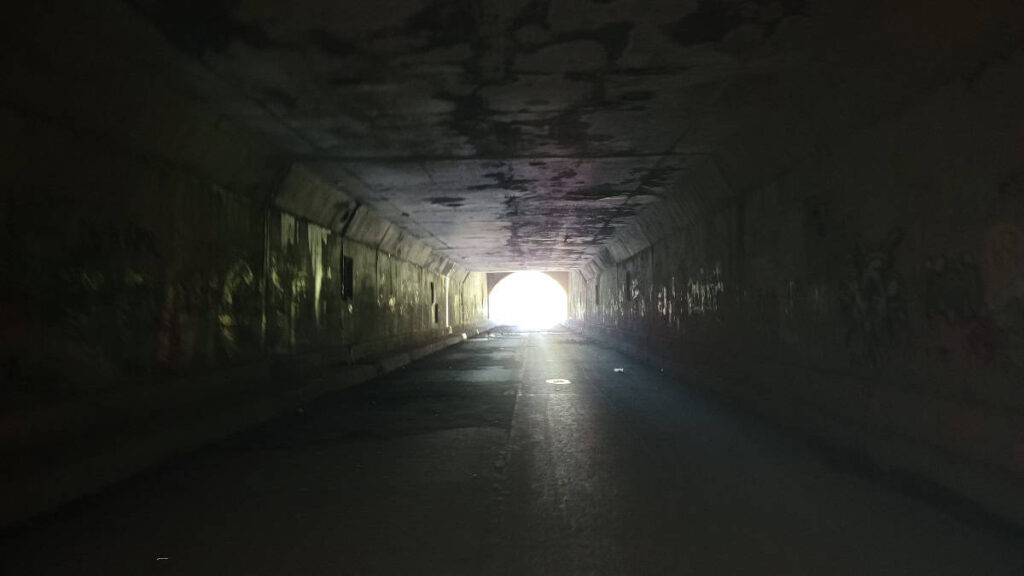 inside the dark Sideling Hill tunnel looking towards the entrance with light shining brightly outside