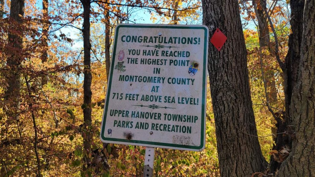 A white sign reads "Congratulations! You have reached the highest point in Montgomery County"