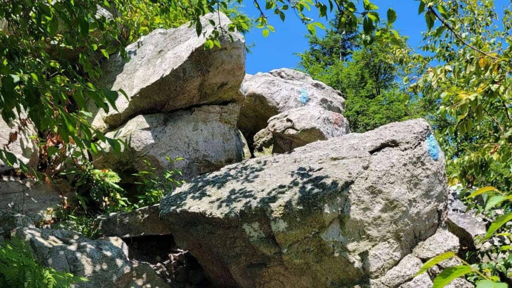 blue painted blazes are seen on large boulders to mark the trail