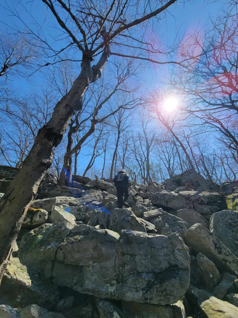 a young boy climbs up a rock scramble along the appalachian trail