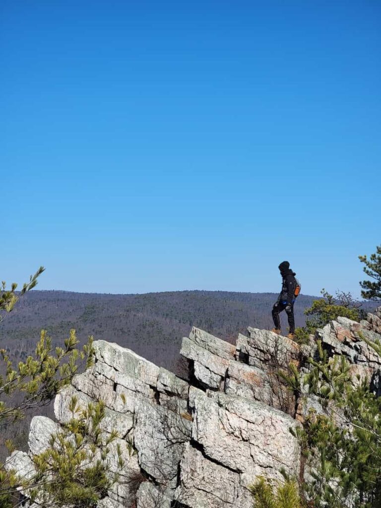 a boy stands on rocks at the Pole Steeple Overlook