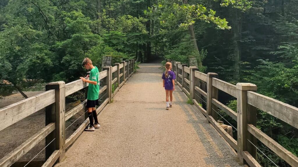 Two young kids look out over the railings of a concrete pedestrian bridge