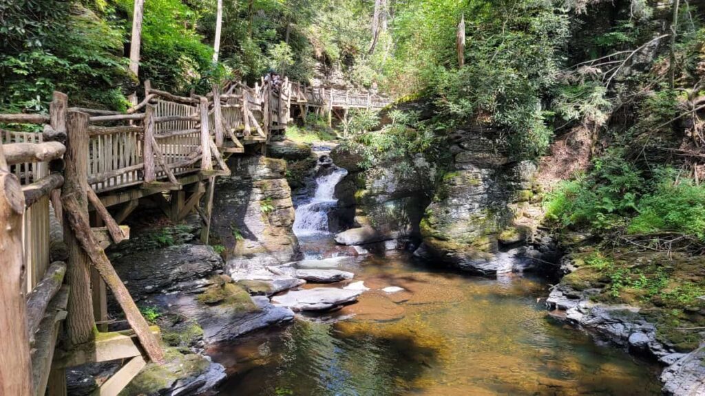 a wooden boardwalk path follows along Bushkill Creek at Bushkill Falls