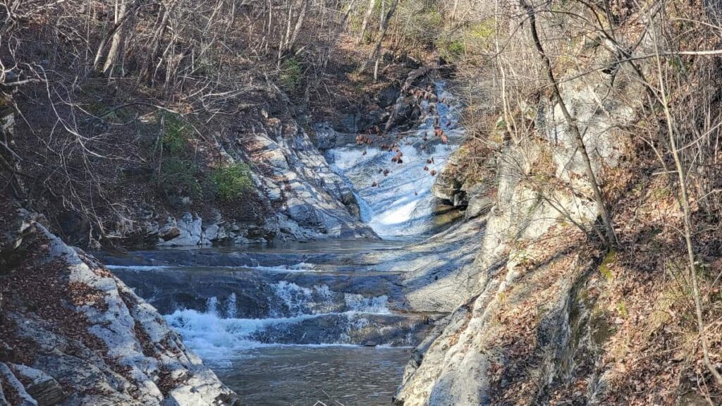 A small waterfall is seen at the end of a worn down path