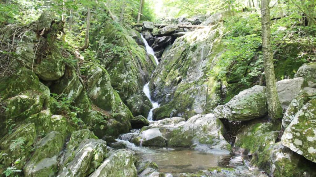 A skinny waterfall flows over large rocks in the forest along the Dark Hollow Falls trail in Shenandoah National Park