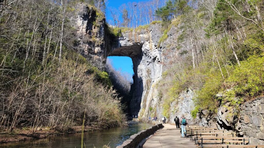 Looking at a natural stone arch with people walking the path underneath in Virginia