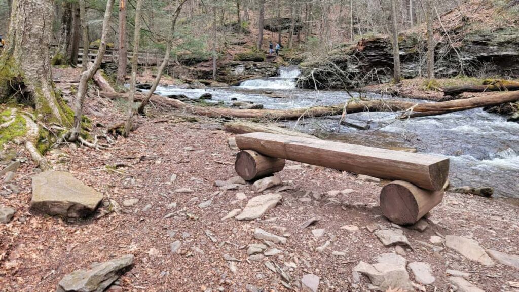 view of a wooden bench with a creek in the background