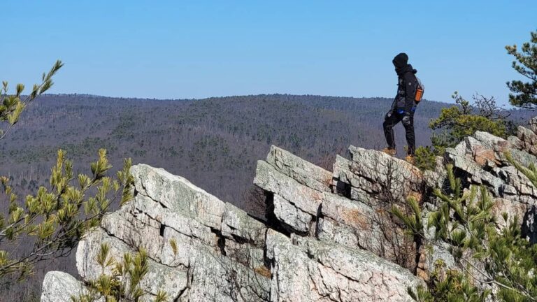 a boy stands on rocks at the Pole Steeple Overlook