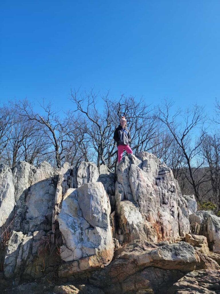 A young girls stands on top of a large white rock outcropping