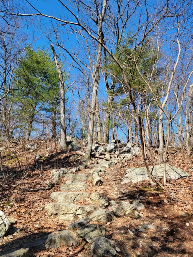 A rocky trails ascends a small mountain to the Pole Steeple Vista