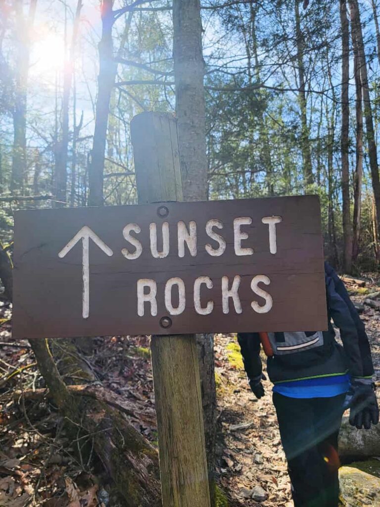 A wooden sign reads "sunset rocks" with an arrow directing the way to the trail