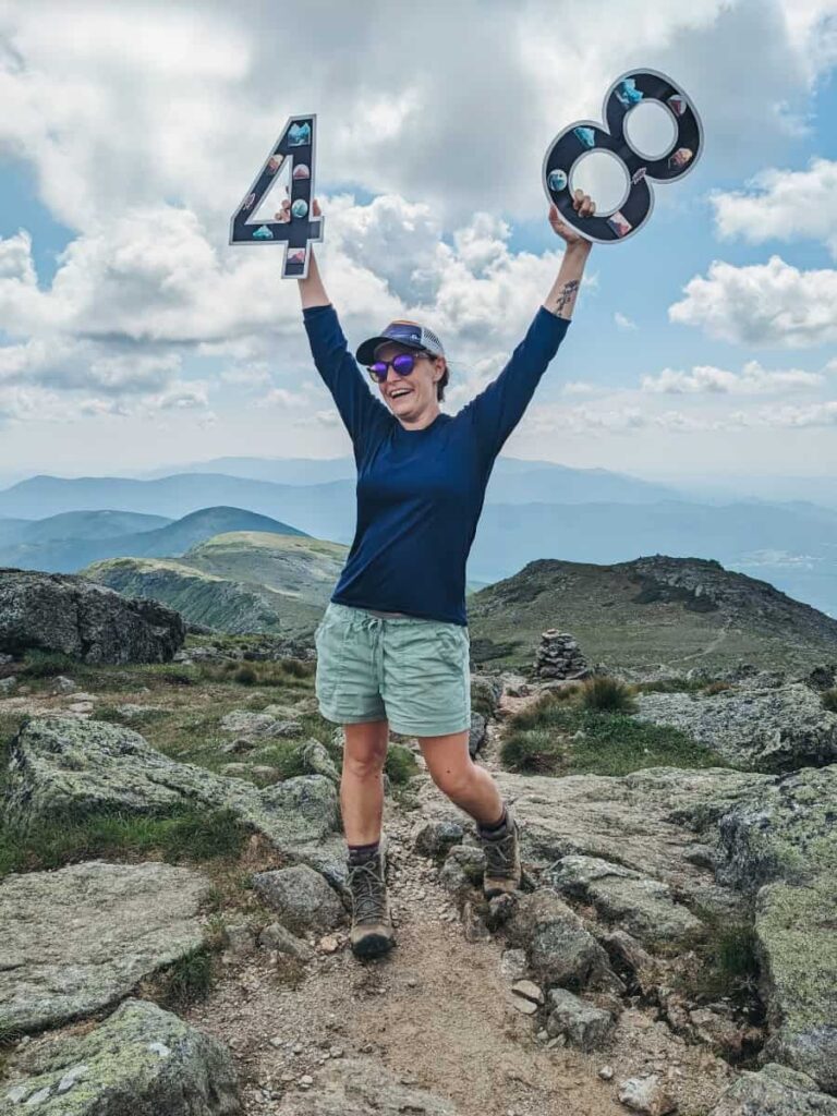 a woman stands on top of a mountain holding the number 48