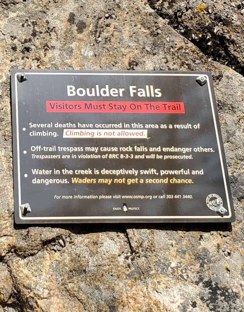 A sign posted on a rock at the Boulder Falls trail warns visitors to stay on the trail